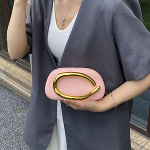Pink leather evening clutch bag featuring a distinctive gold U-shaped metal top handle