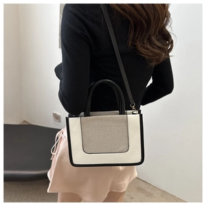 Detailed side view of woman wearing a minimalist color-block crossbody bag in beige and black
