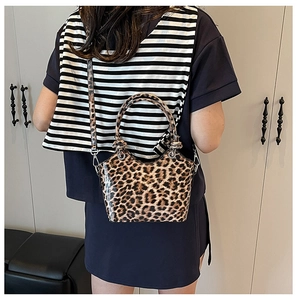 Leopard print handbag with shiny texture and detachable strap shown on a model