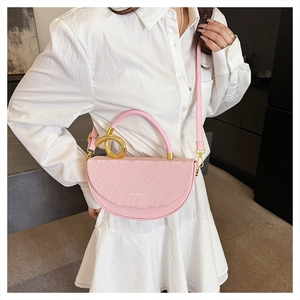 Detail of pink half-moon saddle bag with textured leather and gold circular metal hardware