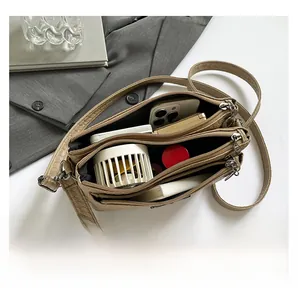 Top view of khaki woven crossbody bag with three zipper compartments and accessories