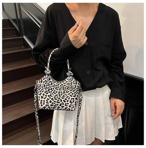 Chic leopard print bucket bag with knotted handles and detachable shoulder strap on steps