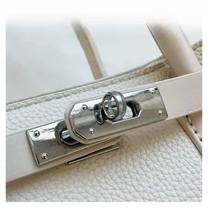 Vue détaillée du fermoir pivotant argenté et de la sangle sur le sac à main beige