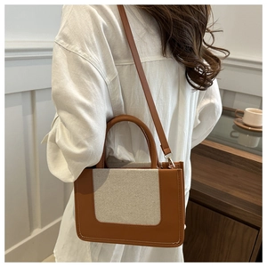 Detailed close-up of stitching on contrast canvas and brown leather crossbody bag