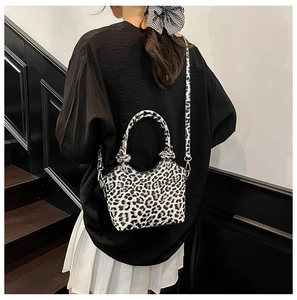 Rear view of a model carrying a mini leopard print bucket bag with a detachable strap