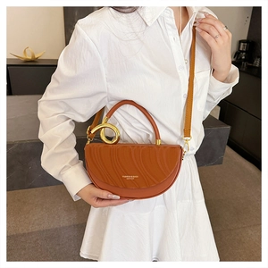 Detail view of caramel saddle bag with wave embossed flap and gold circular metal handle