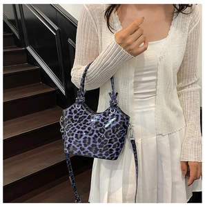 Detail of glossy purple leopard bucket bag featuring dual handles and knotted strap