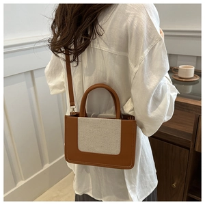 Detail of a brown and beige patchwork handbag with rounded handles and a slim shoulder strap