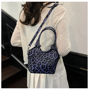 Detail of blue leopard print bucket bag with silver metal eyelets and top handles