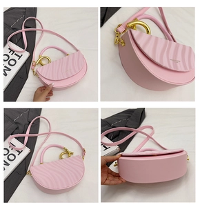 Detail view of pink saddle bag with wave texture cover and golden semi-circle handle