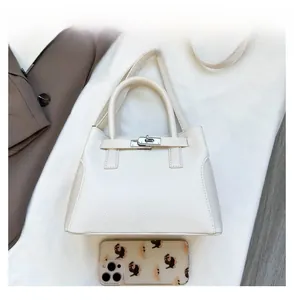 Détail du sac à main en cuir grainé blanc avec comparaison de taille par smartphone