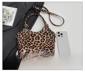 Detail view of leopard print handbag with metal rings compared to a phone for size scaling