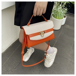 Detail of orange leather and woven fabric Kelly bag with gold rivet lock and shoulder strap
