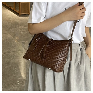 Detail of dark brown woven leather texture on a stylish women's crossbody bucket bag