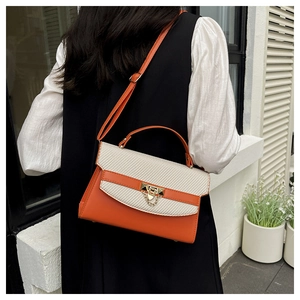 Detail of orange and beige patchwork Kelly bag with gold lock and chain on model