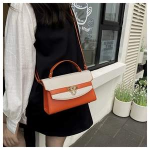 Detail of a two-tone crossbody bag with orange leather and beige woven texture flap