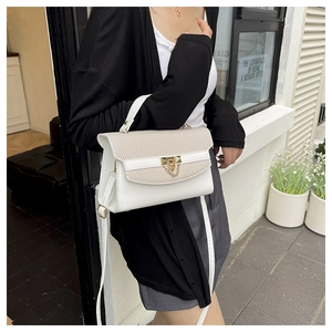 Detail of white and beige patchwork crossbody bag with woven texture and gold hardware lock