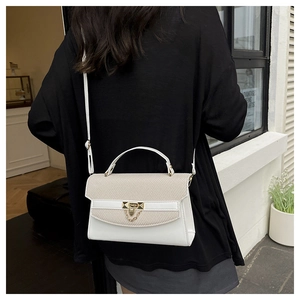 Detail shot of a white and beige woven leather handbag with gold metal lock and chain