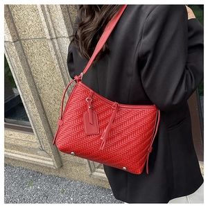 Detail of red woven leather tote bag with metallic base feet and fine shoulder strap