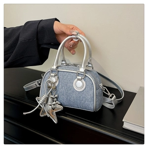Detail of mini denim bowling bag featuring silver star and balloon dog charms