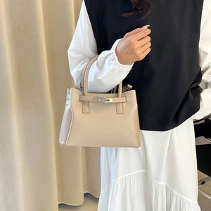 Sac à main en cuir kaki avec texture litchi et boucle argentée porté par un modèle
