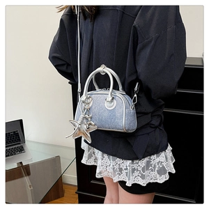Detail of light blue denim bowling bag featuring silver star and balloon dog charms