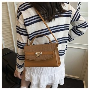 Brown handbag with woven flap, gold chain detail and metallic lock shown on model