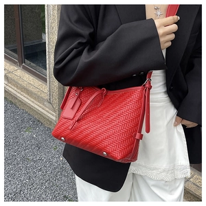 Detailansicht der roten geflochtenen Eimertasche mit V-Muster und Metallnieten am Boden