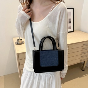 Contrast panel tote bag with black leather and denim texture carried by a model