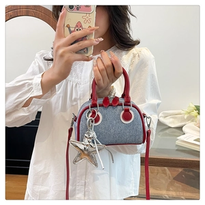 Detail of denim mini Boston bag with red leather trim and a silver star charm