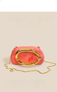 Detailed close-up of pink marble acrylic evening clutch with gold C-handle and snake chain