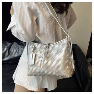Detailed view of silver woven leather bucket bag texture with chic fringe charm tassel
