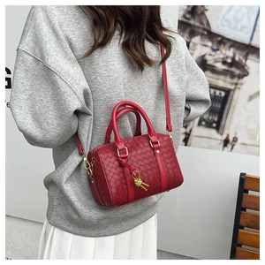 Detail of red woven texture on Boston pillow bag with matte gold metal hardware