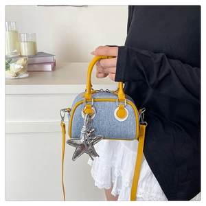 Close-up of contrast denim bowling bag with yellow leather handles and star charm