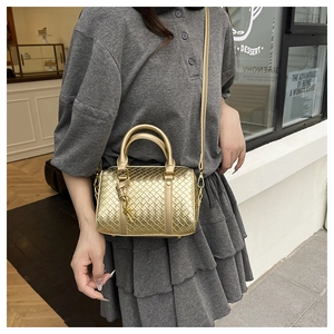 Detail of golden woven Boston bag with metallic texture and detachable shoulder strap