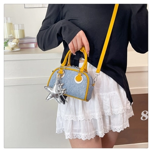 Detail of blue denim Boston bag with yellow handles and oversized silver star charm