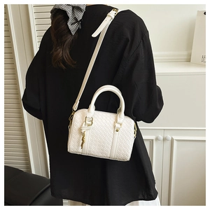 Rear view of a model wearing a white woven Boston bag with gold hardware accents