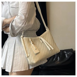 Detail of cream woven shoulder bag with cross-weave texture and adjustable strap