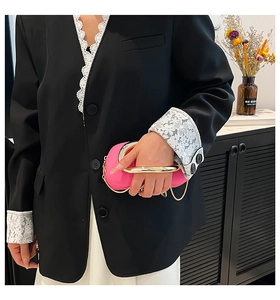 Detail of rose pink evening bag with gold circular metal handle and thin chain strap