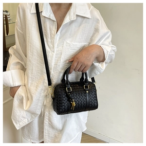 Close-up of black woven Boston bag with intricate knotted details and gold hardware