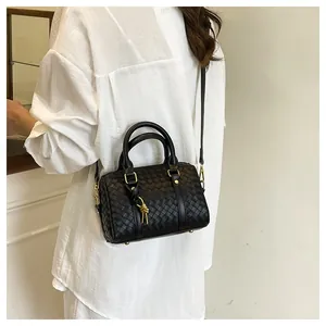 Detailed view of black woven pillow bag with gold knot accents and round handles
