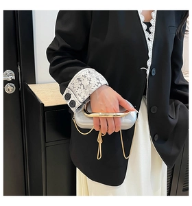Detail of evening clutch with gold metal handle and chain strap held by a model