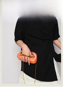 Detail of marble acrylic evening bag with gold circular handle and crossbody chain strap