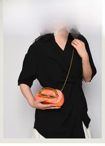Detail of orange marble acrylic clutch with gold round handle and chain strap