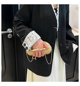 Detail of elegant gold metal clutch bag with vintage round handle and chain strap