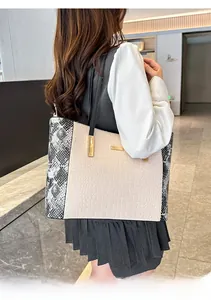 Modella che porta una borsa tote coccodrillo con lati a serpente e finiture dorate