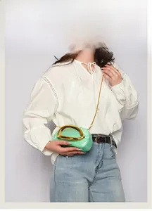 Detail of mint green acrylic clutch with marble texture and gold U-shaped metal handle