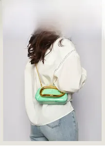 Detail of light green marble acrylic clutch with chunky gold metal U-shaped handle