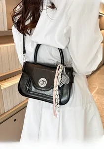 Dettaglio borsa nera lucida con texture vintage, serratura argento e ciondolo da tennis