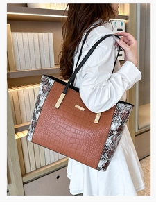 Dettaglio patchwork con trama a coccodrillo e stampa serpente su una borsa tote